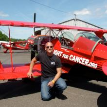 Back view of red biplane with a person standing in front of the wing.