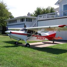 Side view of white and red monoplane with single engine. Registration number N318KM is painted in red near the rear of the fuselage.