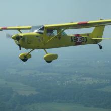 Side view of lime green monoplane in flight with one engine and fixed landing gear. The registration number "N5353Q" is painted near the rear of the fuselage.