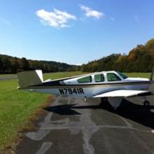 Side view of white monoplane with single engine and black and yellow accent colors. The registration number "N7941R" is written in black near the rear fuselage.