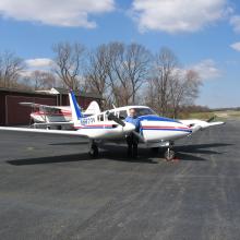 Diagonal front and side view of white aircraft with blue and red accent colors and twin engines.