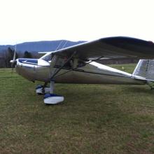 Side view of white and blue monoplane with single engine and fixed landing gear.