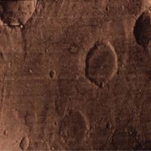 A partial view of Mars from orbit, showing off craters on the surface.