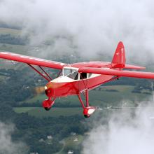 Front view of red and white monoplane with one engine and fixed landing gear.