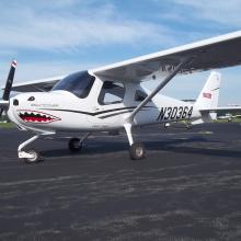 Side view of a white monoplane with a single engine and fixed landing gear. A shark mouth decal is on the front of the cockpit and registration number "N30364" is painted in black near the rear of the fuselage.