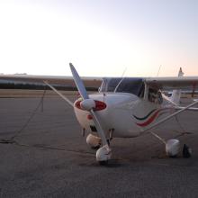 Front view of a white monoplane with a single engine and fixed landing gear.