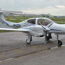 Side view of white and blue monoplane with twin engines. Registration number "N420A" is painted in blue near the rear of the fuselage.