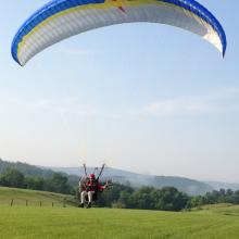 Front view of one-person paraglider with blue, yellow, and white fabric.