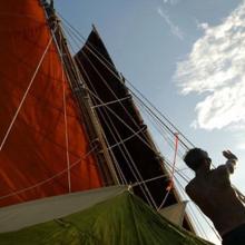 A person on a sailboat uses their hands to determine direction.