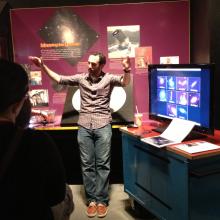 A museum expert discusses astronomy with visitors inside a museum gallery.