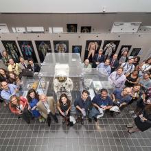 A large group of people stand around an museum exhibit featuring spacesuits.