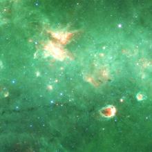 A partial view of a green-colored nebula inside the Milky Way with many orange-colored sections throughout.