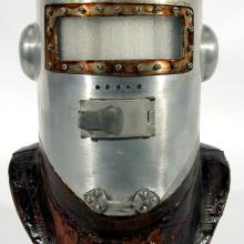 A primitive pressure helmet which looks like a knight's helmet with metal full-body face guard and darker-colored brim for attachment to the rest of a pressurized suit.