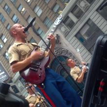 A group of Marine Corps musicians perform as part of a rock band.