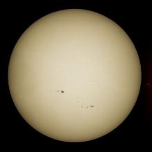 Three side-by-side disk views of the Sun. The left disk features sunspots visible through magnetic fields and they appear as dark spots surrounded by lighter spots called phages. The middle disk reveals the sunspots visible on the surface of the Sun. The right disk reveals the sunspots as dark spots surrounded by lighter-coloured phage clouds in the Sun's atmosphere. Prominences of gases floating off the edges of the disk are also visible.