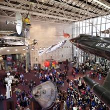 An exhibit inside the Washington, D.C. National Air and Space Museum building featuring multiple artifacts that are critical milestones in flight.