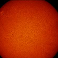 Partial disc view of the Sun's atmosphere. A sunspot cluster is visible on the upper left quadrant of the disk.