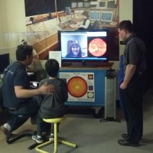 Four museum visitors video chat with a museum expert on astronomy inside the Museum's observatory.