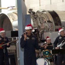 A group of U.S. Air Force musicians perform at the Museum. They are wearing red and white Santa hats.