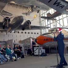 A musician from the U.S. Air Force performs as part of a band at the Museum. They are wearing a red and white Santa hat.