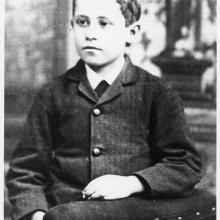 Black and white portrait of a boy sitting in a chair.