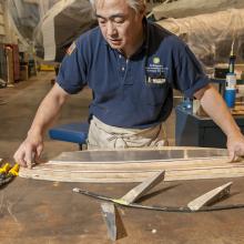 A male staff member of the museum's Collections Department works on restoring part of a World War II era bomber in the museum's restoration hangar.