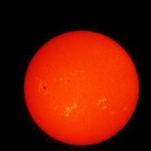 Disk view of the Sun's atmosphere. Sunspots (seen as dark spots) and phages (lighter-colored clouds) are visible on the disk.