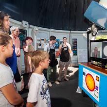 Museum visitors video chat with an expert on astronomy inside the Museum's observatory.