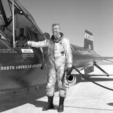 Joe Walker, a white man, stands next to a record-breaking experimental rocket plane that he flew.