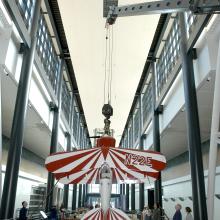 A red and white biplane is lifted into its display position above visitors at the Museum's Steven F. Udvar-Hazy Center.