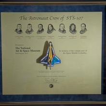 A plaque honoring the members onboard the Space Shuttle Columbia during the STS-107 disaster with their faces and a depiction of the shuttle engraved into the plaque.