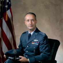 Gen. James A. McDivitt, a white male, sits for a professional portrait in his U.S. Air Force uniform.