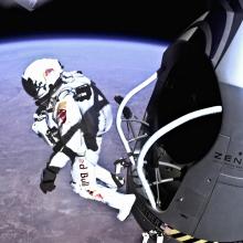 Felix Baumgartner, a pilot wearing a white high-altitude suit, jumps from near space as part of a flight test.