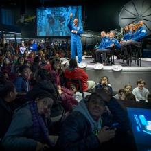 A former astronaut gives a thumbs up gesture to a camera streaming a video chat with astronauts on the International Space Station.