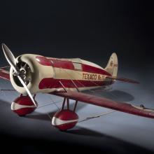 White and red monoplane model with one engine. "Texaco No. 12" is painted in red near the rear of the fuselage.