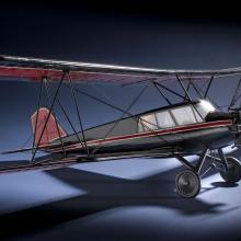 Side view of red and black biplane model with one engine. 