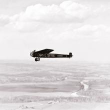 The T-2, a monoplane which attempted the first transcontinental flight, flies above land.