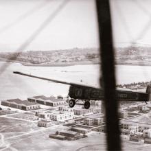 The T-2, a monoplane which attempted the first transcontinental flight, flies over a town prior to landing near San Diego, California.