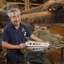 A male museum specialist holds a rubber object he made.