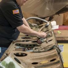 A museum specialist works on cleaning a door of a military monoplane.