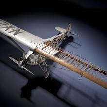 Top view of cutaway model of the Spirit of St. Louis, a silver-colored monoplane with one engine.