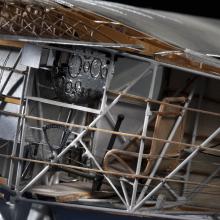 Close-up view of the interior of a cutaway model of the Spirit of St. Louis, a silver-colored monoplane with wooden and metal parts.