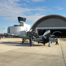 A group museum specialists work to move a gray and black monoplane into its permanent display spot inside the Museum's Steven F. Udvar-Hazy Center.