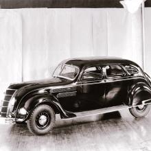 Side view of dark-colored antique car with four seats.