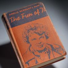 Orange and black book cover featuring a drawing of Amelia Earhart. The book is titled "The Fun of It" and is written by Amelia Earhart.