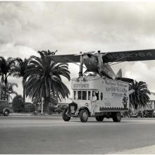 A Piper Cub J-4A, a monoplane with one engine, is displayed on a truck as part of an advertisement.