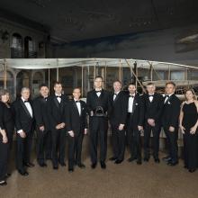 A group of individuals stand together with a trophy at an event hosted by the Museum.