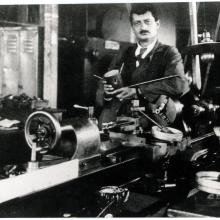 Hermann Julius Oberth, a white man, stands behind a table with primitive rocket parts.