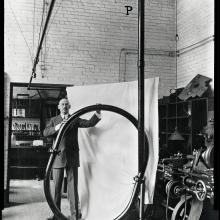 A white man stands while holding a large rounded tube.