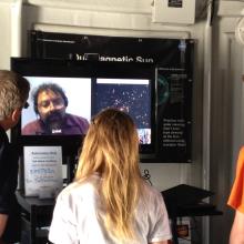 Three museum visitors speak with a male expert on astronomy on video chat at the Museum's public observatory.